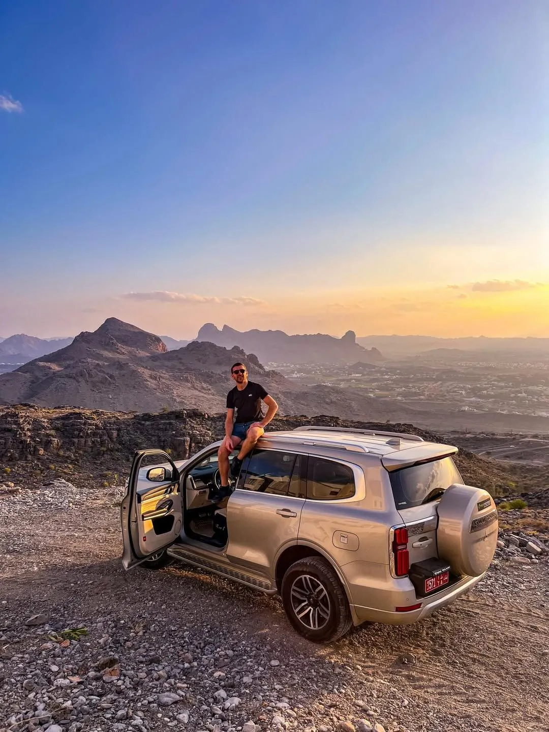 A white 4x4 vehicle parked near a desert canyon in Oman