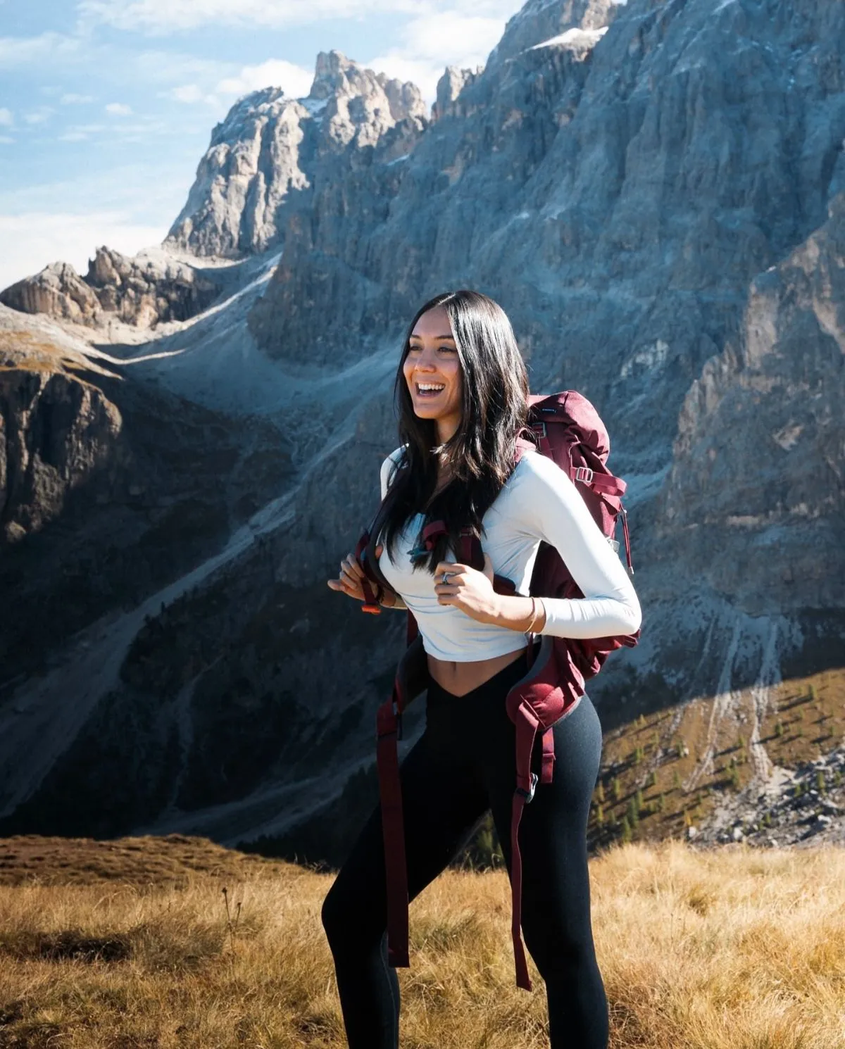 Hiker in warm clothing overlooking a misty Dolomite valley in October