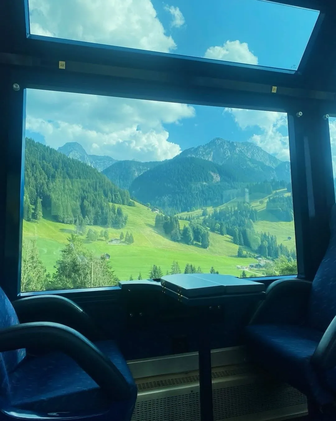 Hand holding a train ticket with green Bavarian countryside visible through the window