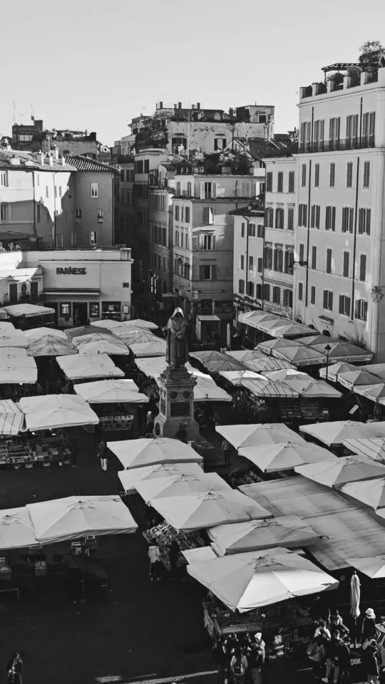 Colorful fruit and vegetable stalls at Campo de Fiori market in Rome under morning sunlight