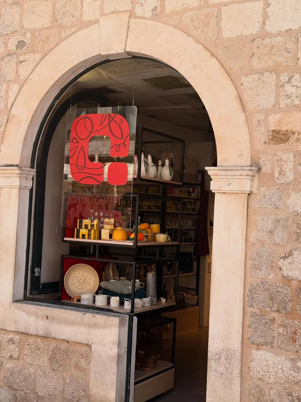 Shelves in a Croatian supermarket displaying local olive oil and fresh fruit