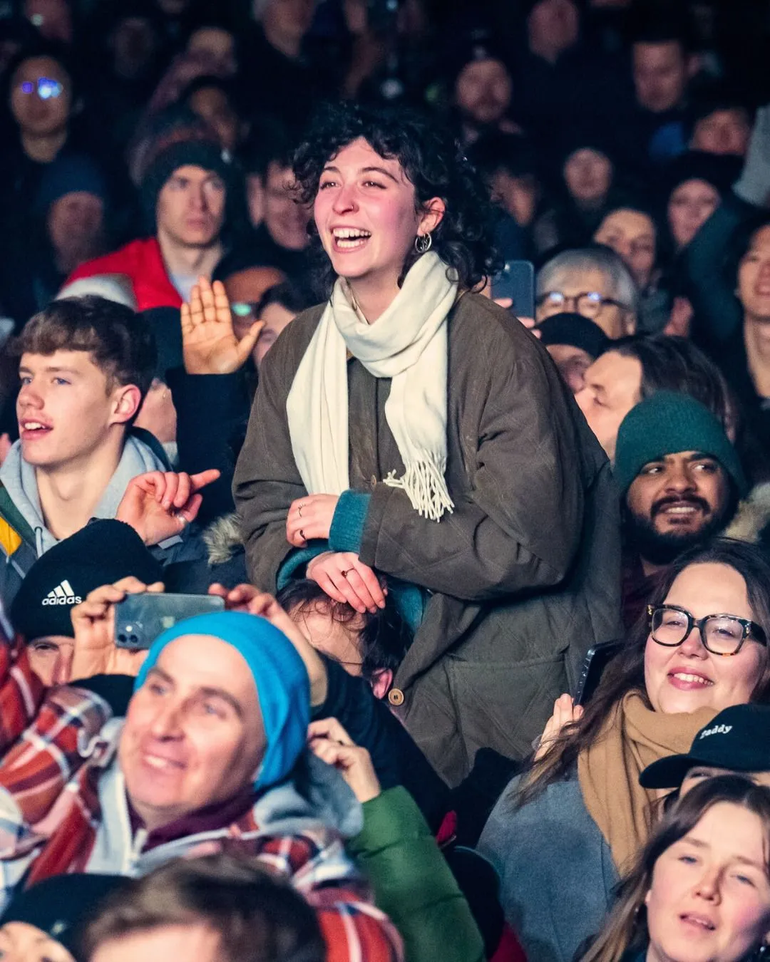 A family with young children in colorful winter gear watching fireworks over Edinburgh Castle during Bairns Afore in West Princes Street Gardens.