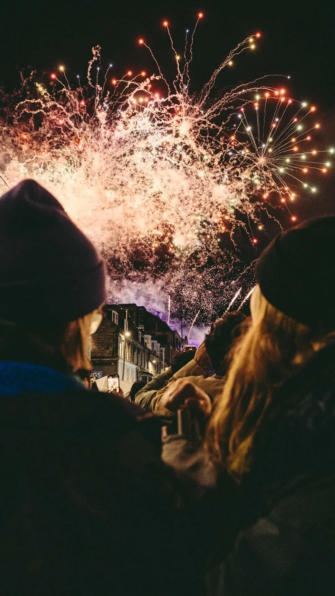 Colorful fireworks exploding over Edinburgh Castle during the Bairns Afore family celebration with crowds in Princes Street Gardens.