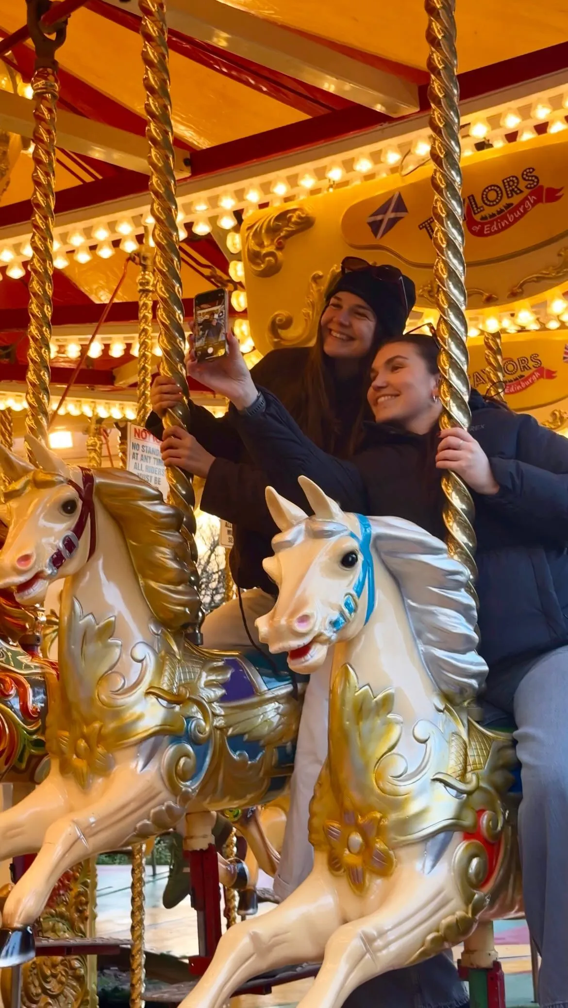 A family walking through the festive Edinburgh Christmas market with twinkling lights and market stalls on a cobblestone street.