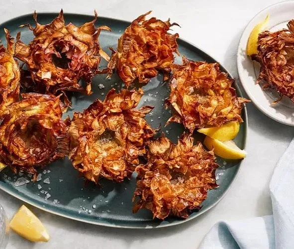 Golden fried Roman artichoke served on a plate in a rustic Italian restaurant setting