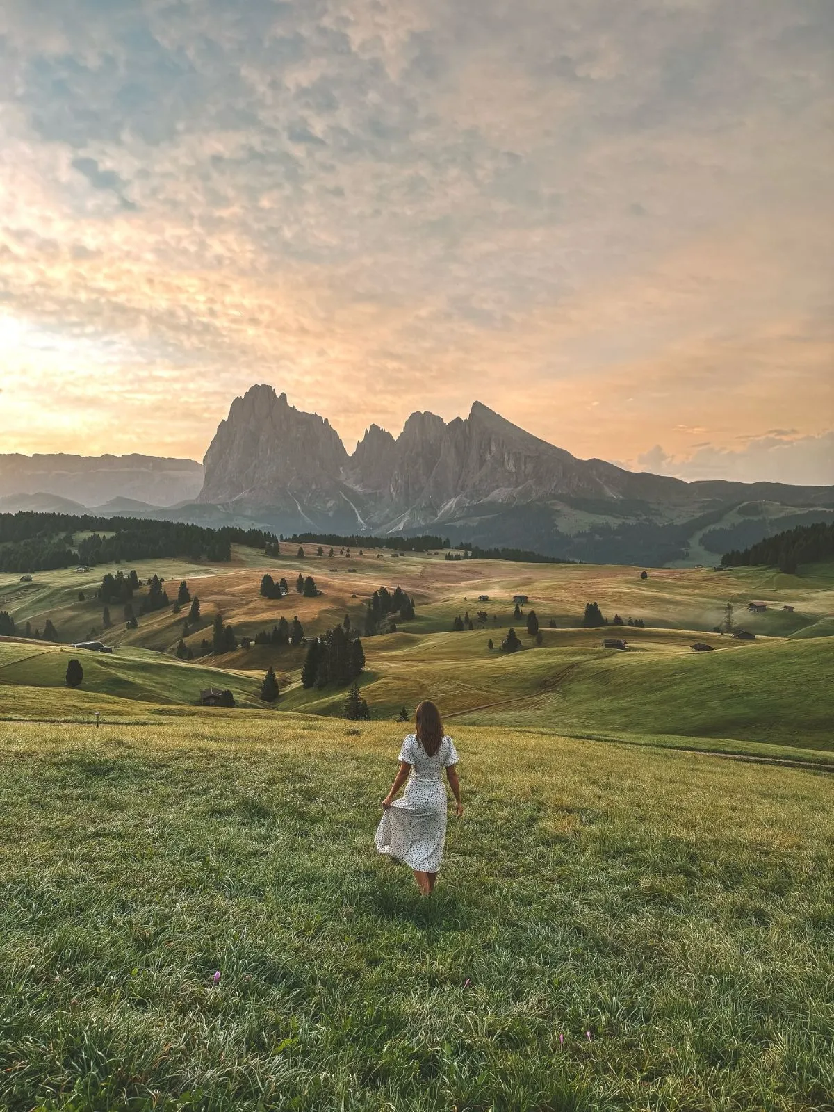 Hiker walking on a green trail in Alpe di Siusi with Schlern mountain in background