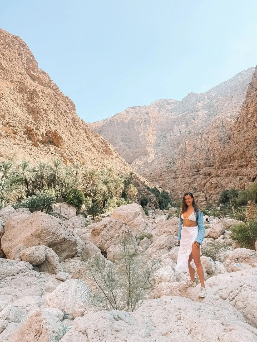 Hiking trail through a rocky canyon with palm trees in Wadi Shab