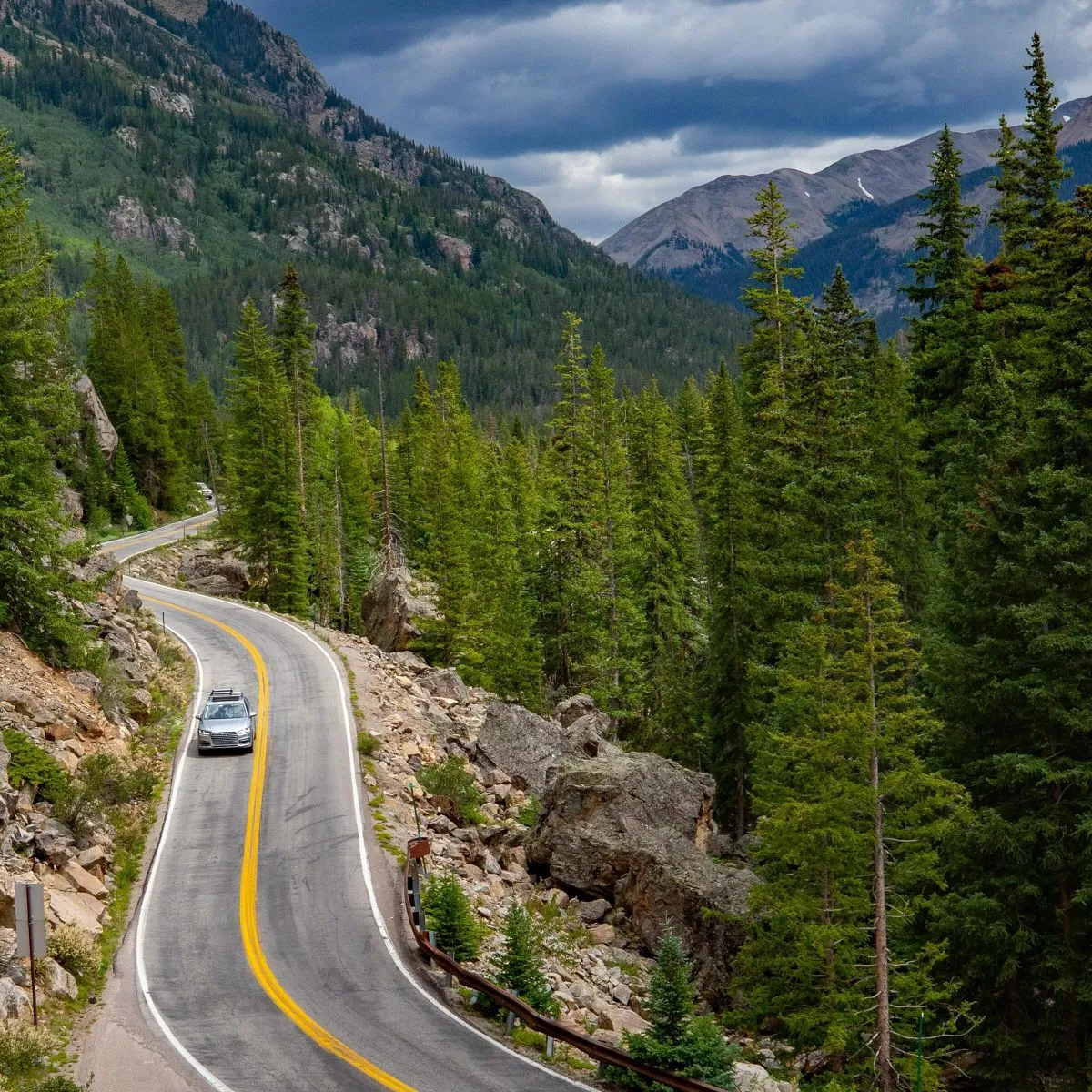 Winding paved road of Independence Pass surrounded by autumn aspen trees leading to Twin Lakes