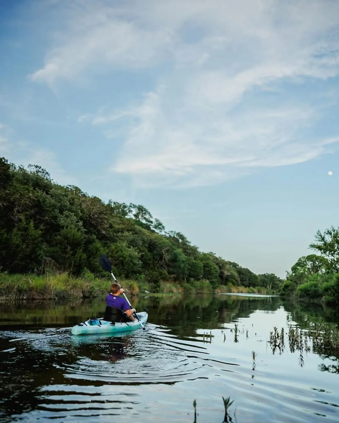 Kayak paddle splashing in calm water near the green marshes of Croton Point