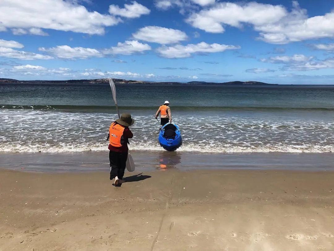 Yellow kayak resting on the sandy shore of Kingston Point Beach with Rondout Lighthouse in the background