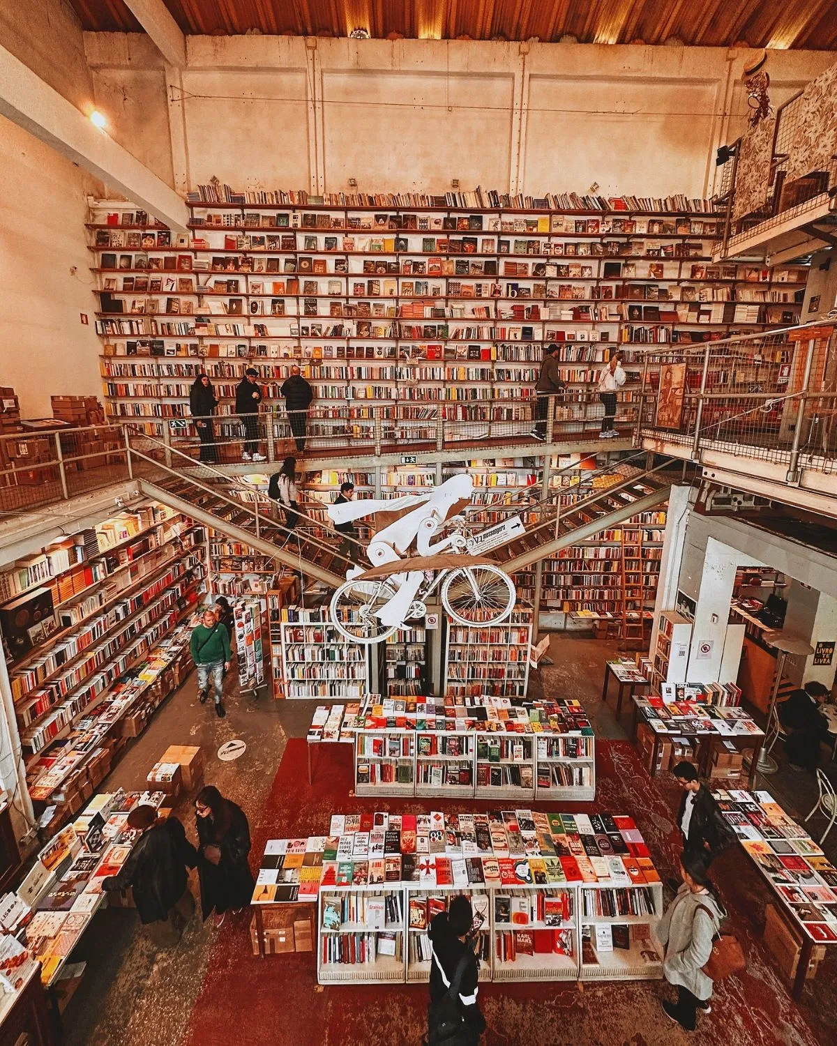 Interior of Ler Devagar bookstore in Lisbon featuring a hanging bicycle and printing press