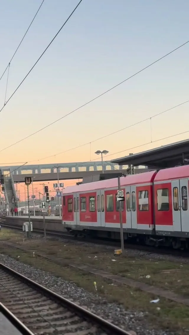 Red Deutsche Bahn regional train waiting at a platform in Munich with mountains in the background