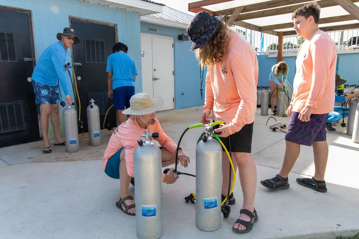 Dive master checking scuba equipment on a boat deck in Tanzania