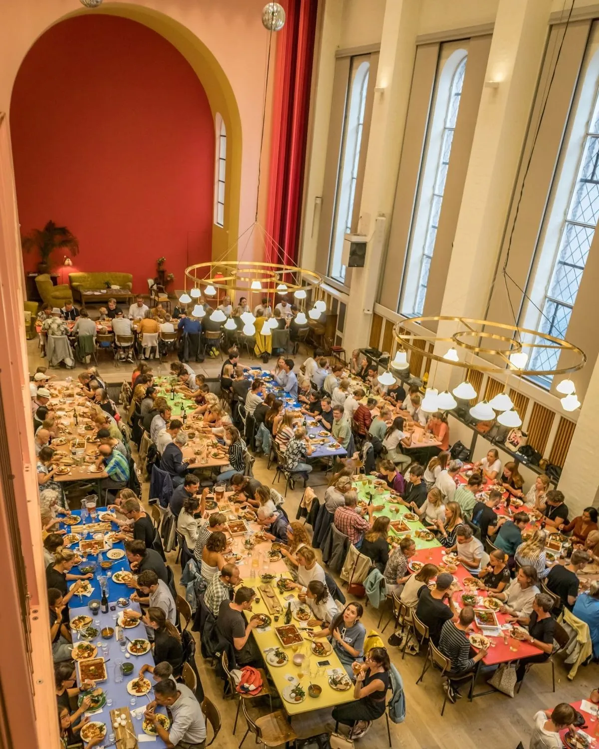 Hands passing a large bowl of food across a communal table during dinner at Absalon