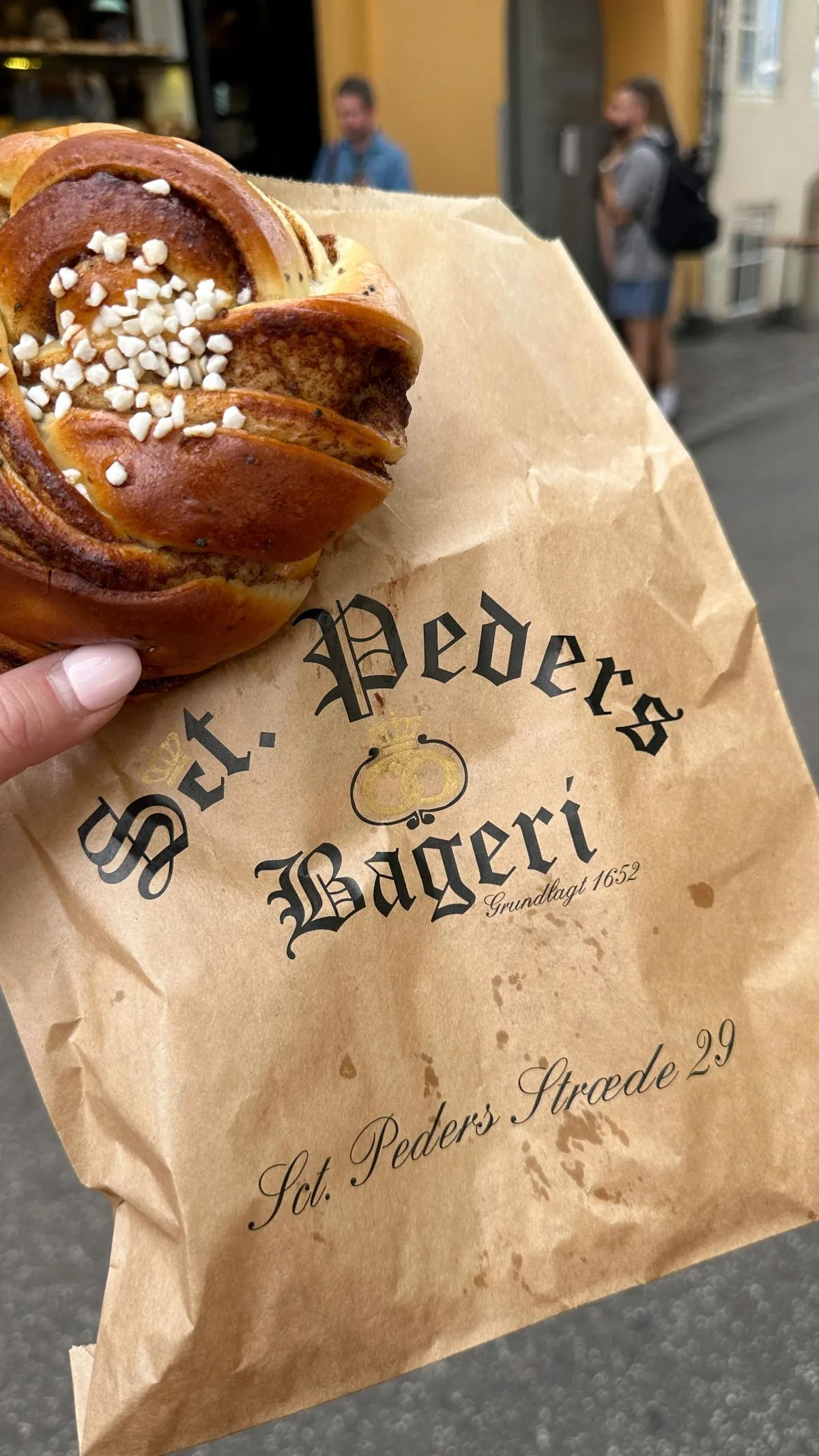 Fresh glazed cinnamon roll on a wooden table at Skt Peders Bageri in Copenhagen