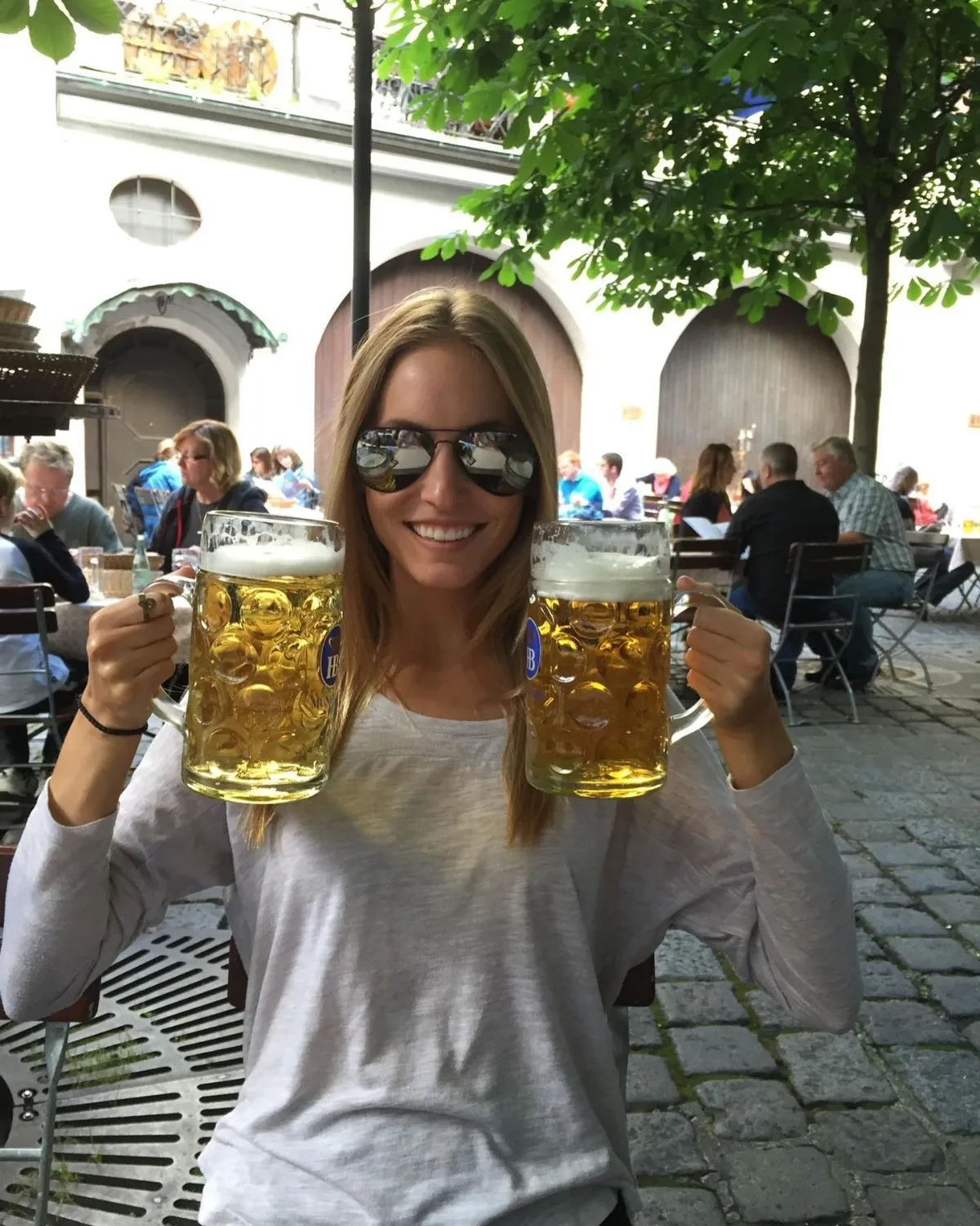 People clinking beer steins at a communal table in Munich