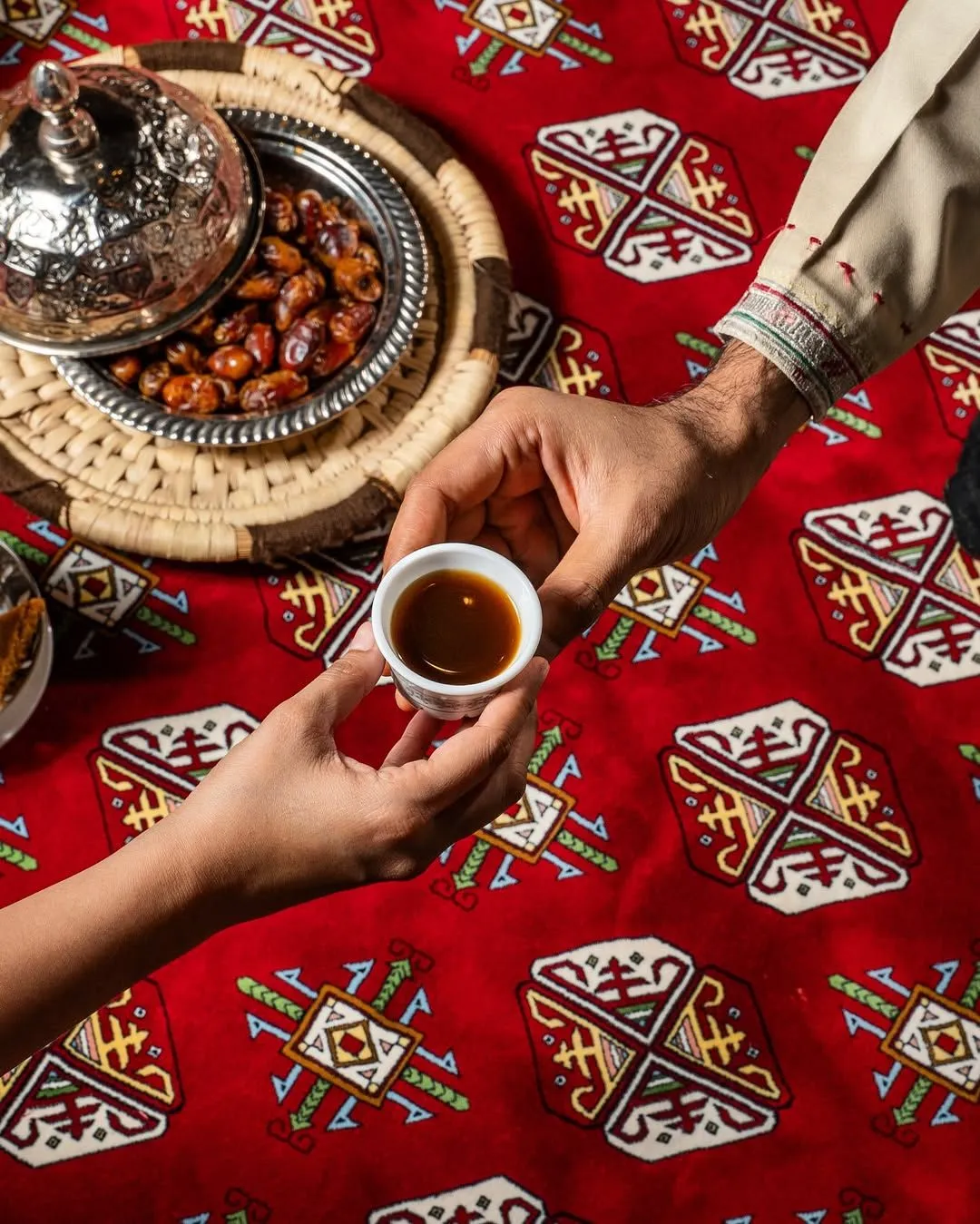 A silver dallah coffee pot and a bowl of fresh dates served in a Bedouin tent.