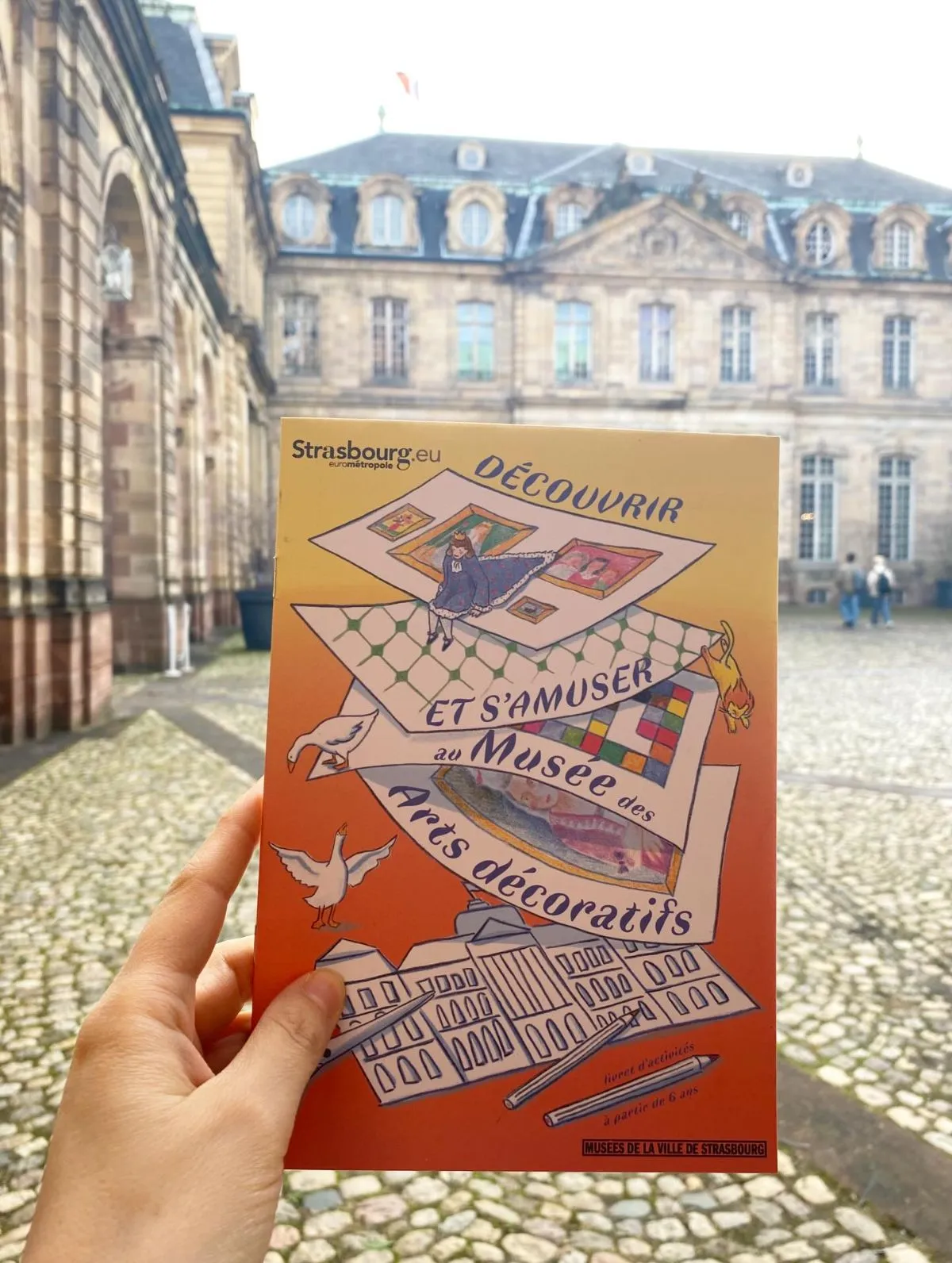 A wooden table with brochures and a sketchbook in front of a museum window