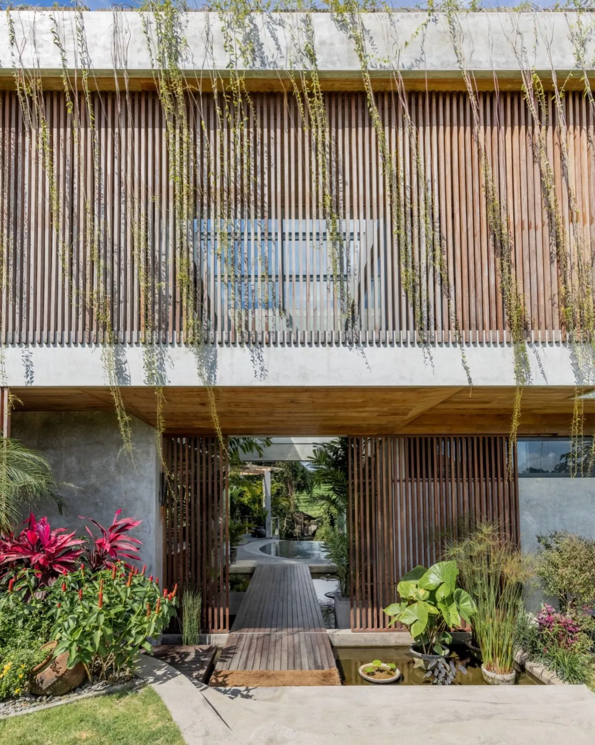 Warm wooden entrance of MasMara Resort in Pererenan with tropical plants
