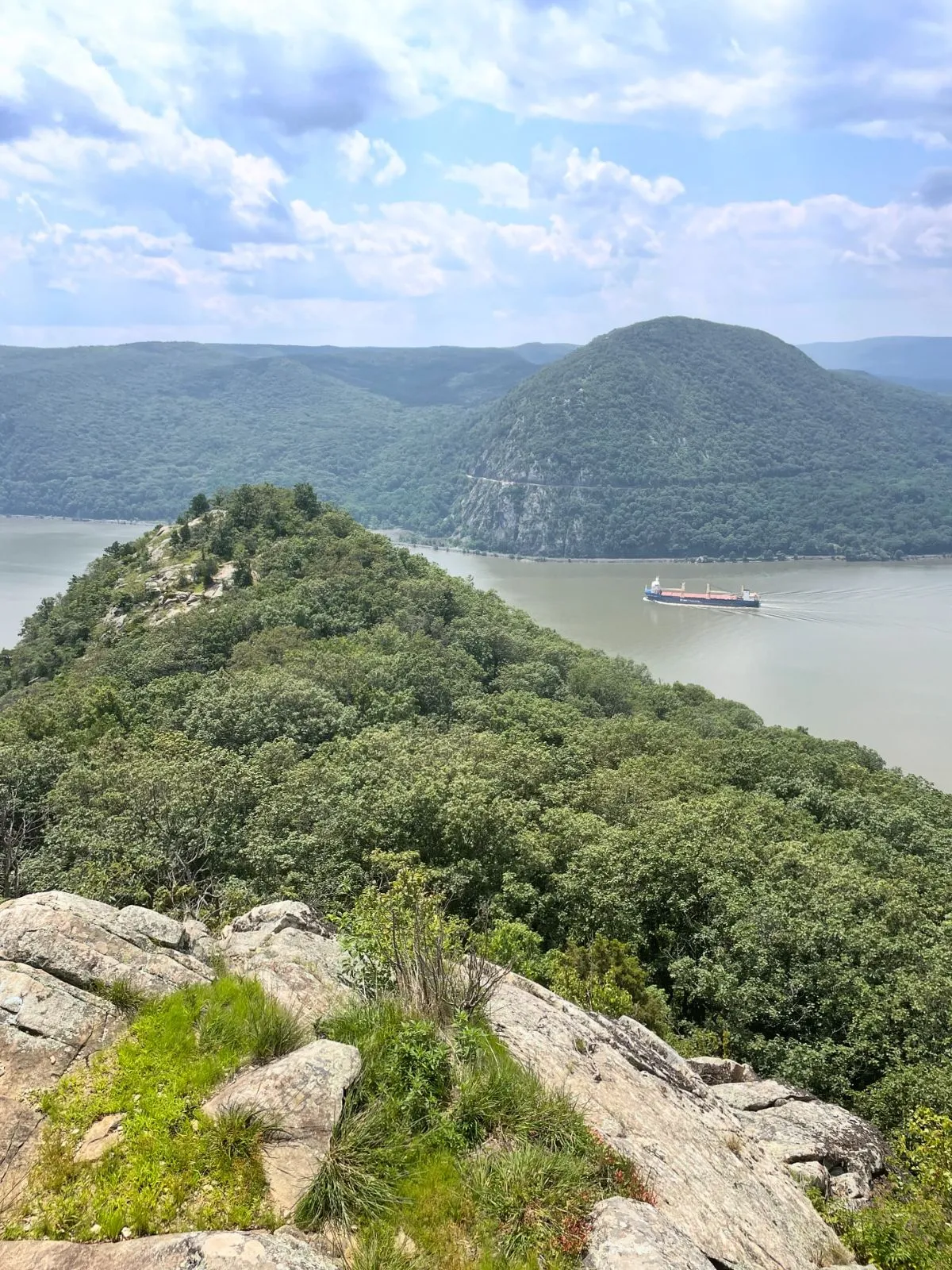 Hiker climbing steep rocks at Breakneck Ridge overlooking the Hudson River