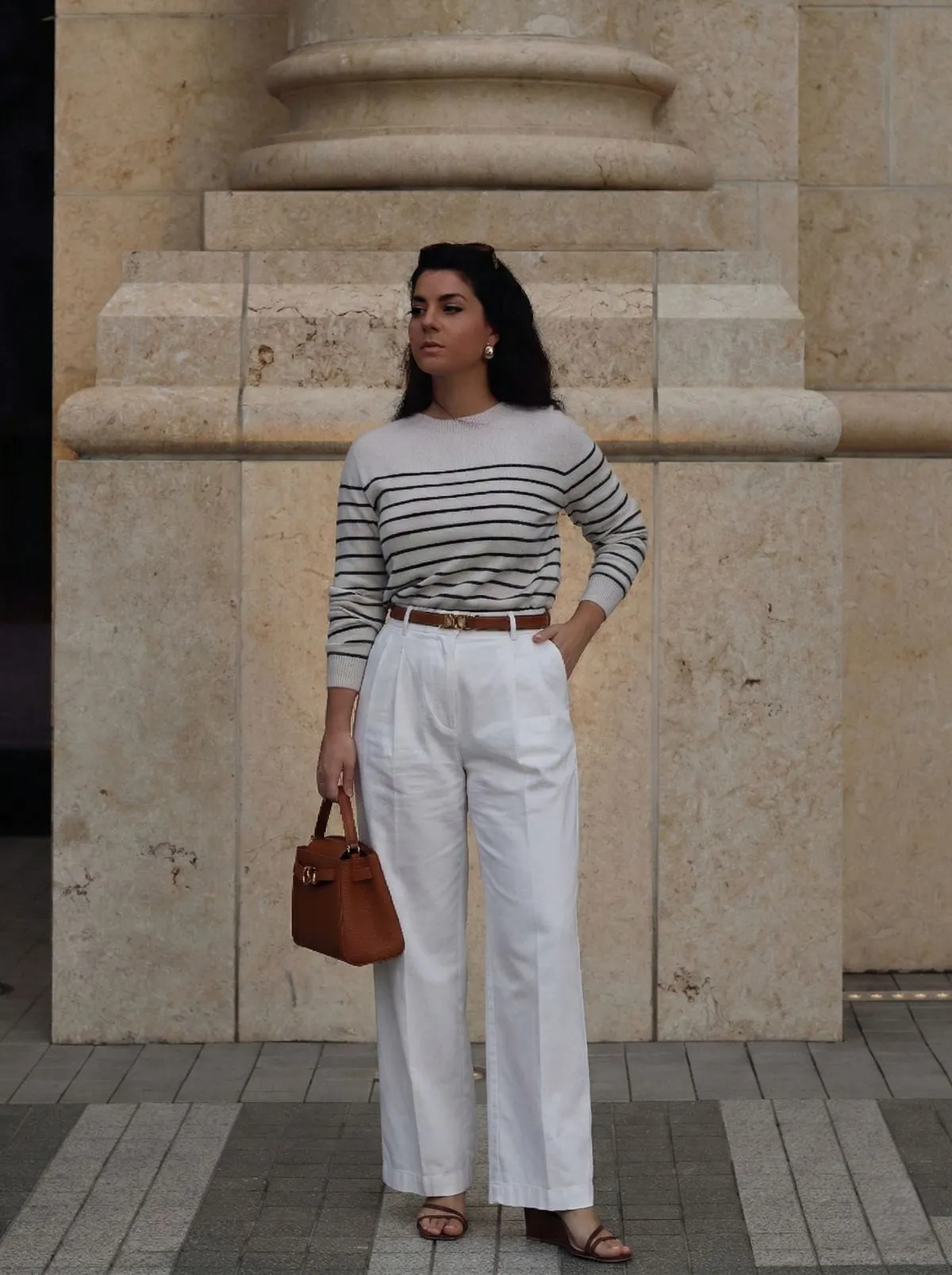 Woman wearing classic Breton stripe top and beige wide-leg trousers on a bridge in Paris