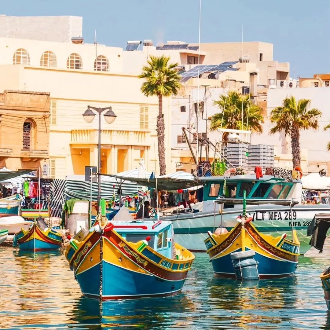 Brightly colored traditional Luzzu fishing boats docked in Marsaxlokk harbor Malta