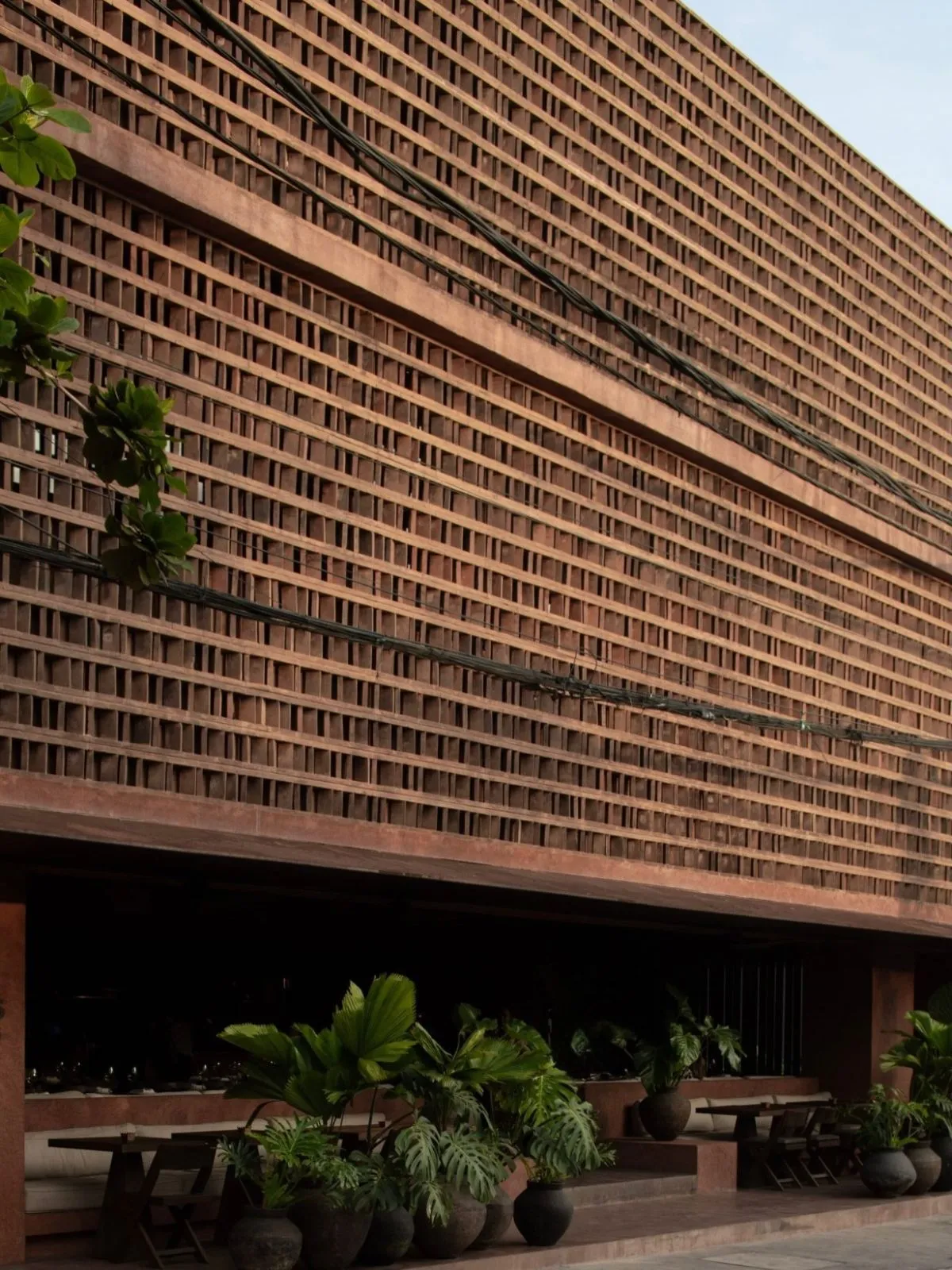 Modern brutalist architecture of Further Hotel in Pererenan with red bricks and tropical plants.