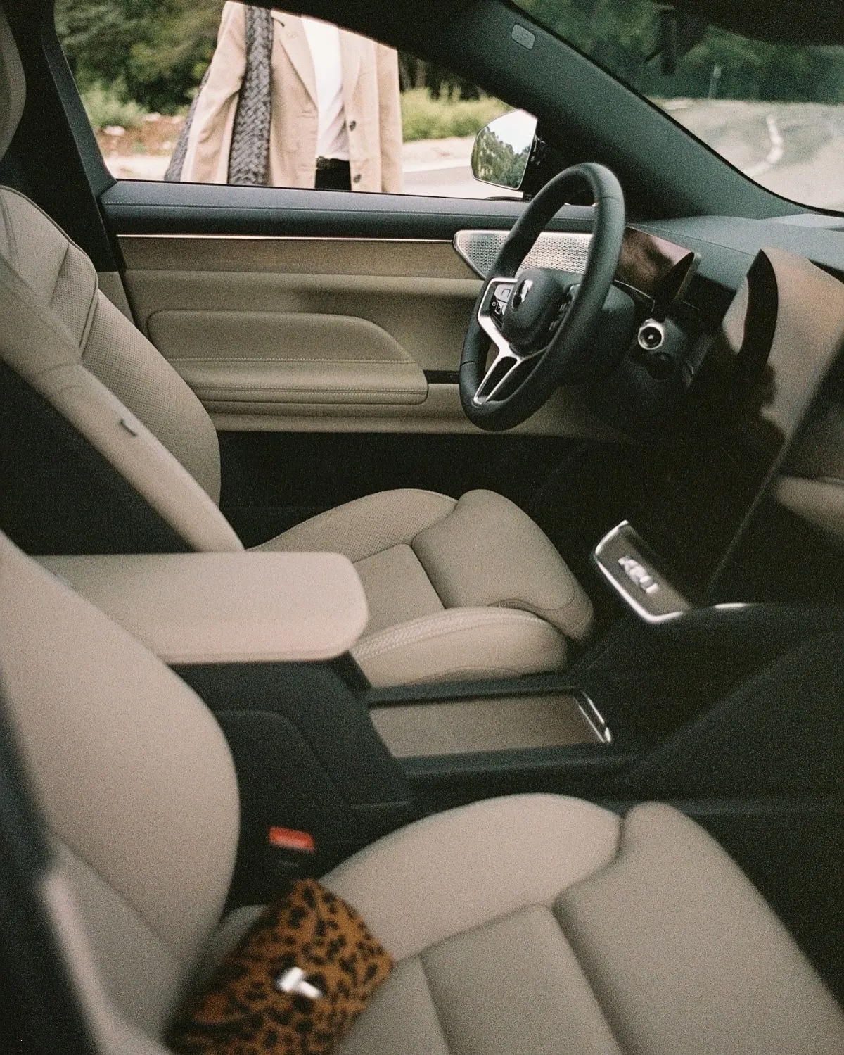 A rental car parked on a scenic French road in summer with a high-visibility vest inside.