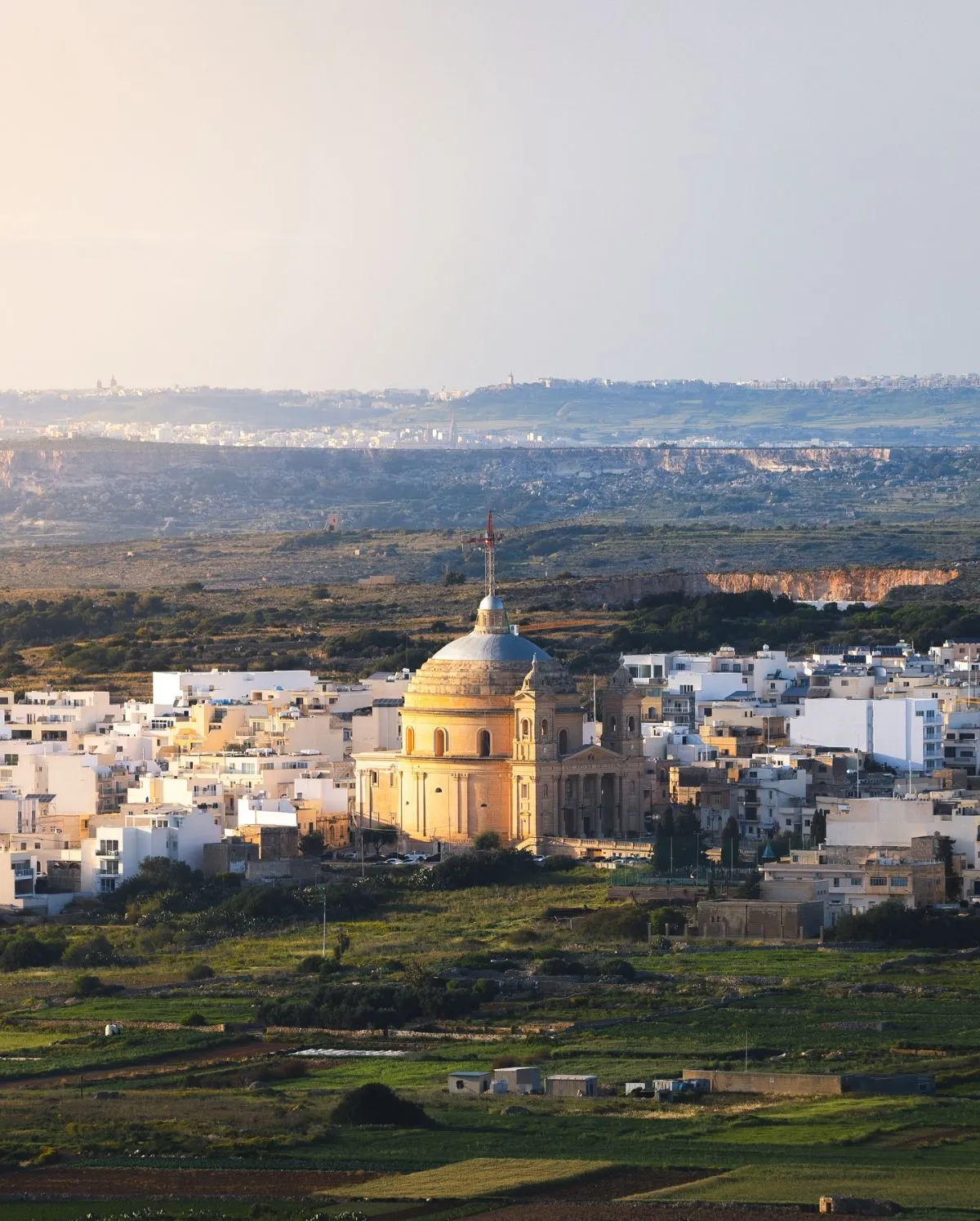 Illuminated Mgarr Parish Church behind a busy traditional Maltese restaurant terrace