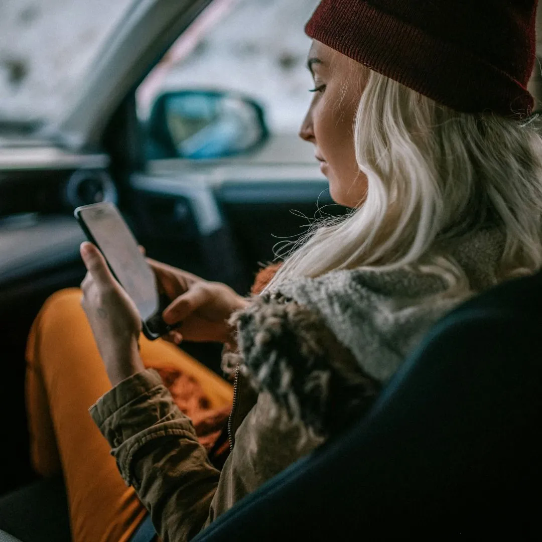 Woman checking travel safety tips on phone inside a car