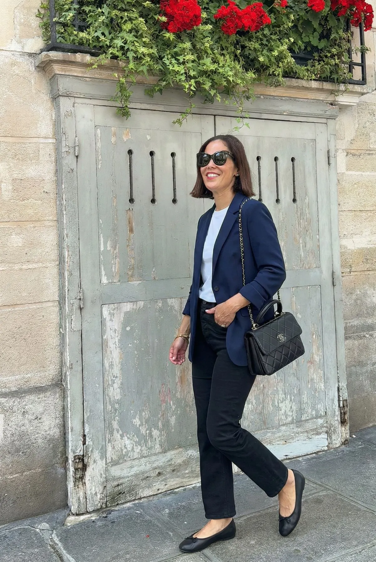 Woman wearing navy blazer and ballet flats walking in Le Marais Paris during summer