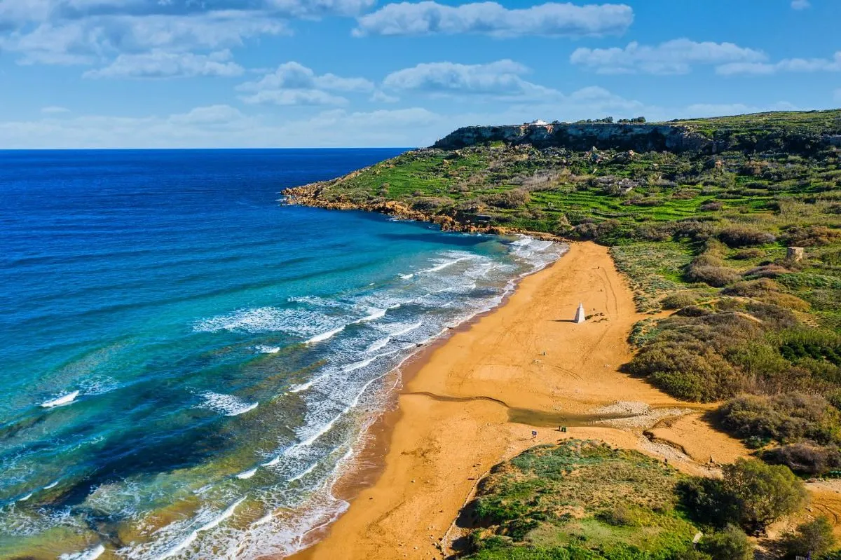High-angle view of the orange sand at Ramla Bay and the surrounding green coastal cliffs in Gozo.