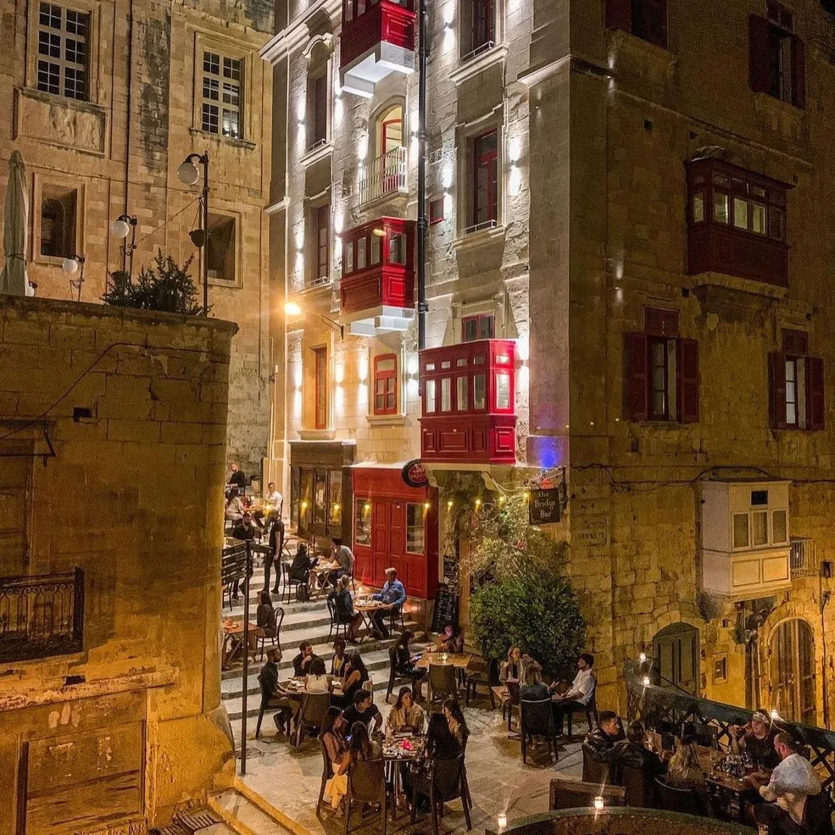 Crowded Strait Street in Valletta at night with warm lighting and wine bars