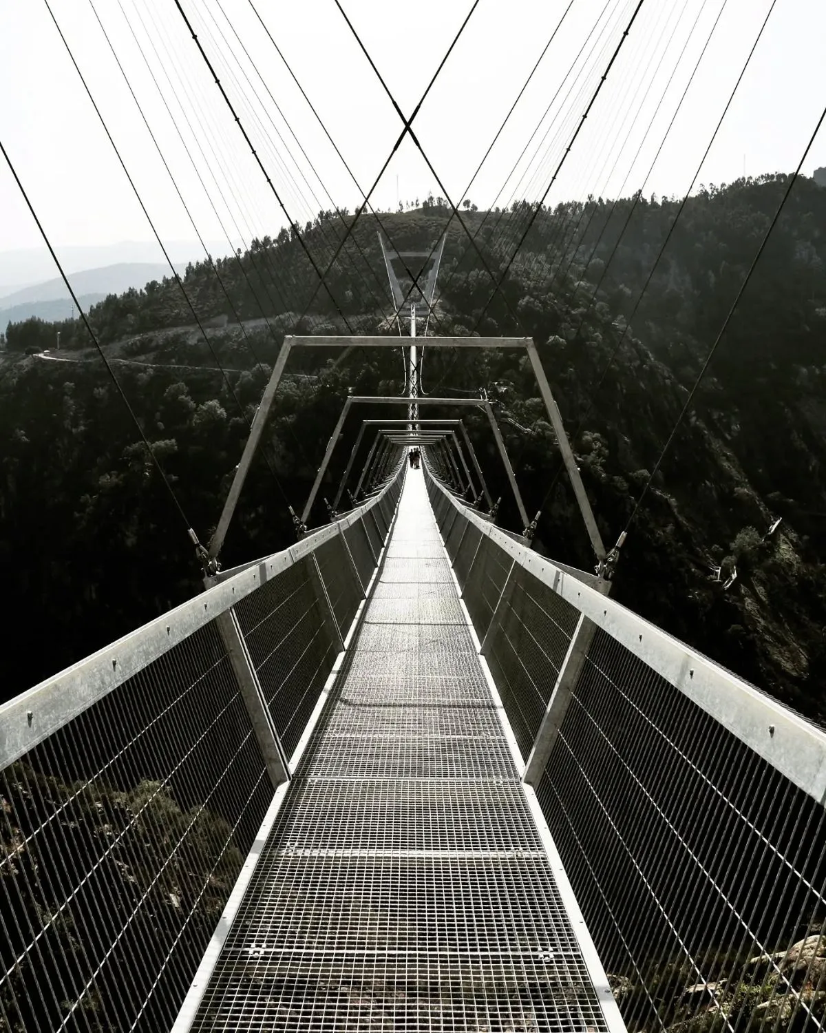 Looking down through the metal grid floor of the 516 Arouca suspension bridge at the river below