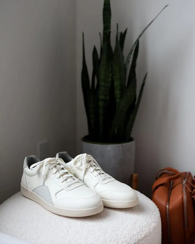 Woman wearing comfortable white sneakers standing on cobblestone street in Paris near a cafe