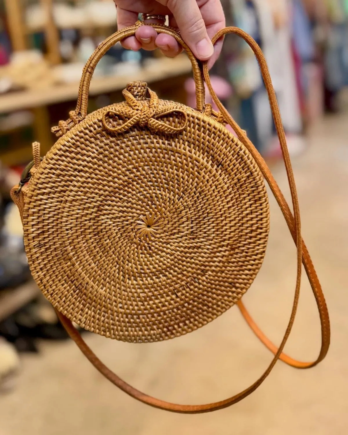 Woman holding a round rattan bag on a cobblestone street