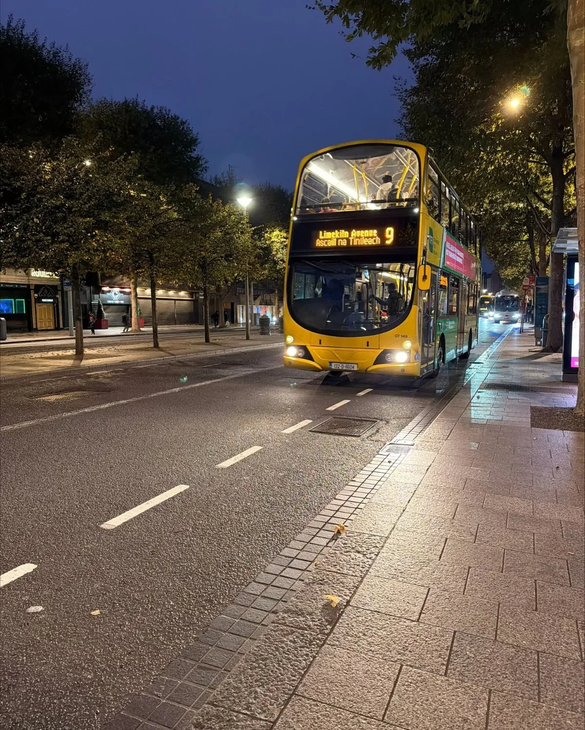 Yellow and blue public transport bus driving in a Dublin suburb
