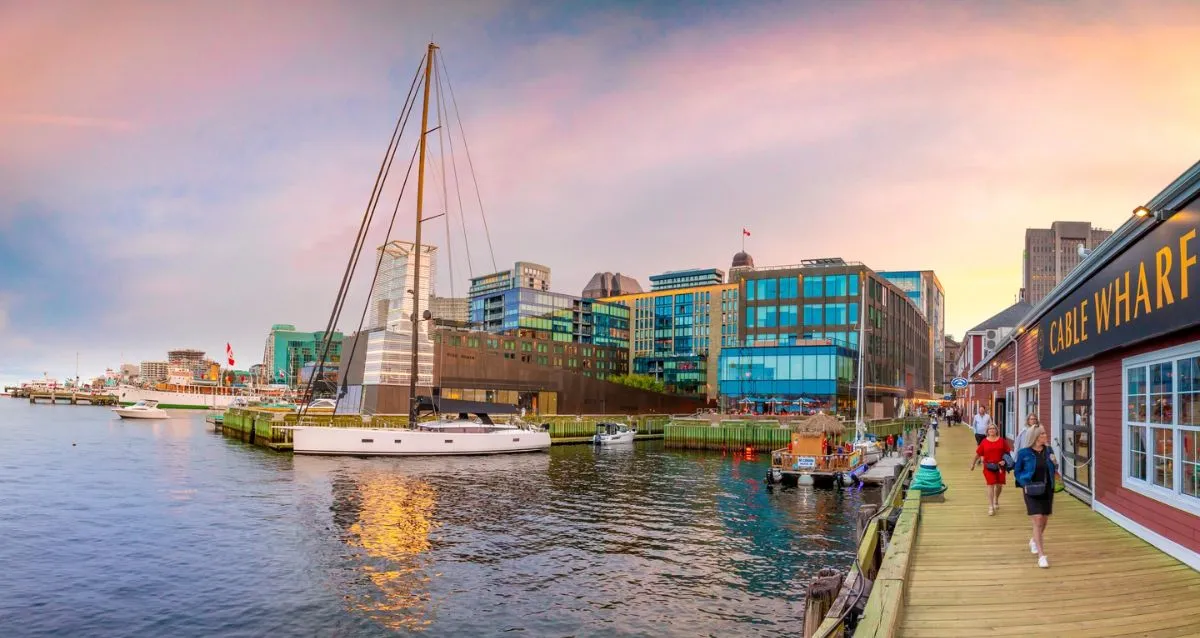 Solo female traveler walking along the sunny Halifax waterfront boardwalk