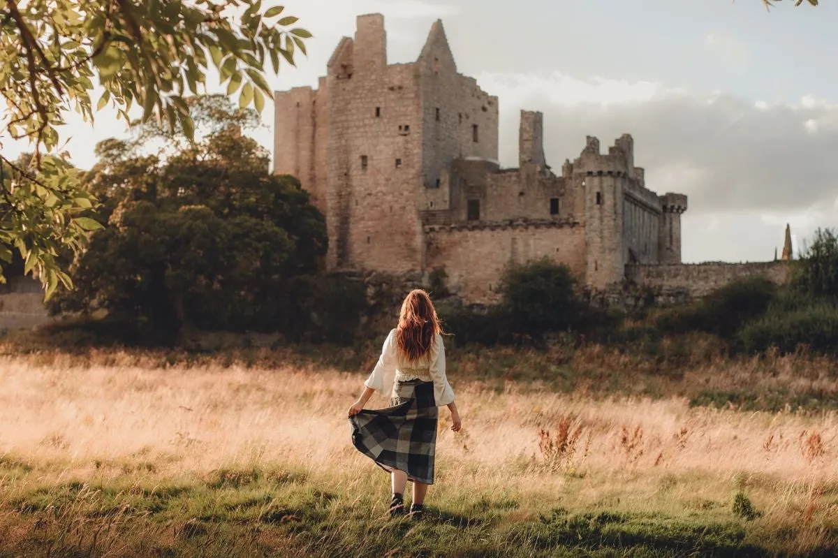 The ancient stone tower house and medieval battlements of Craigmillar Castle near Edinburgh on a sunny day.