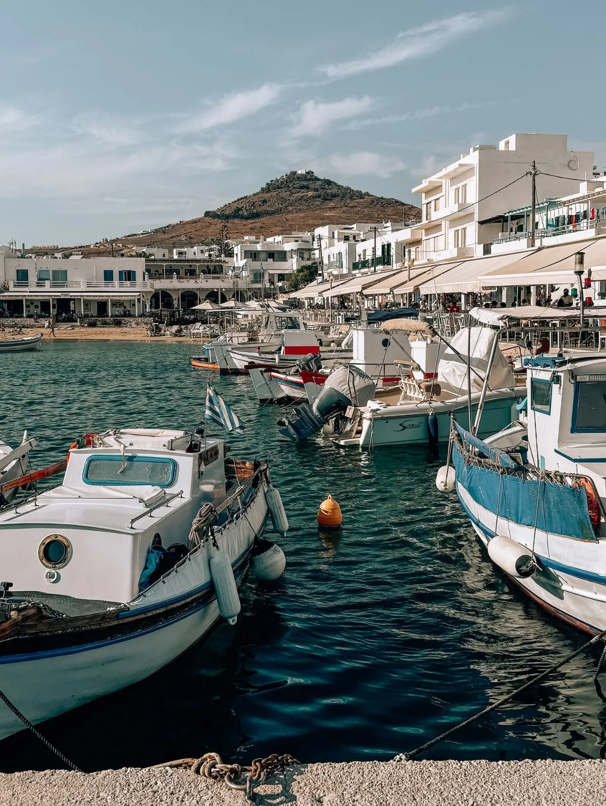 A scenic view of a coastal road in Paros, Greece, representing the island's public transportation routes.