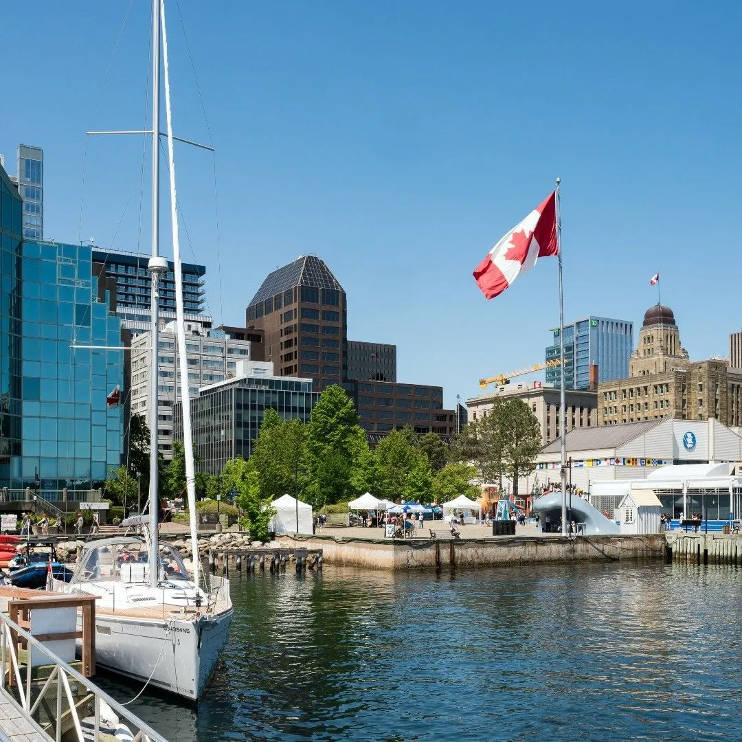 A solo female traveler looking out at the ocean from the Halifax Waterfront Boardwalk in Nova Scotia, Canada.