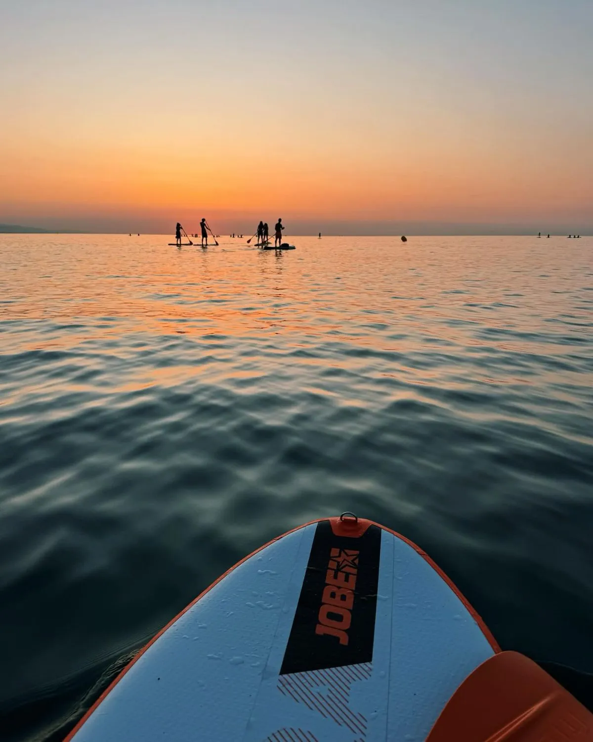 Wooden paddleboard gliding on the calm waters of the Oka River estuary at golden hour