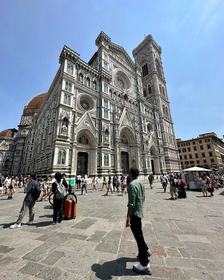 A line of tourists waiting outside the Florence Cathedral under a bright sky