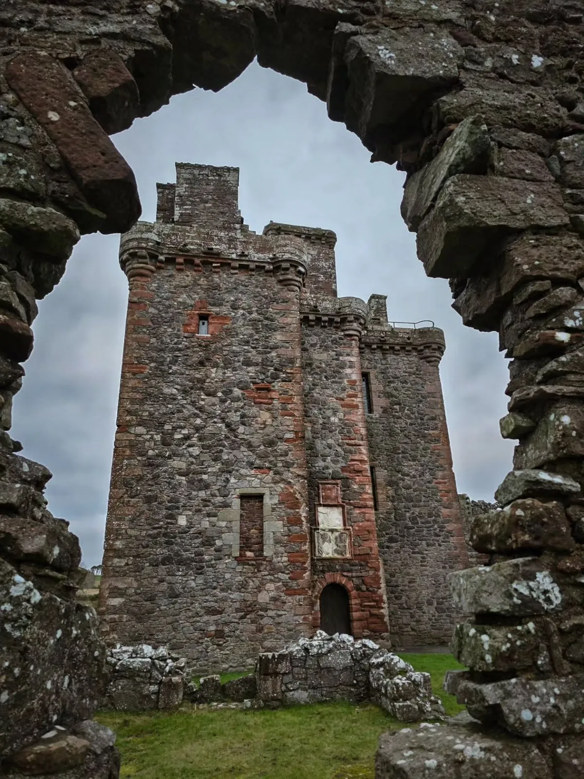 Dirt walking path through green Scottish fields leading to Crichton Castle