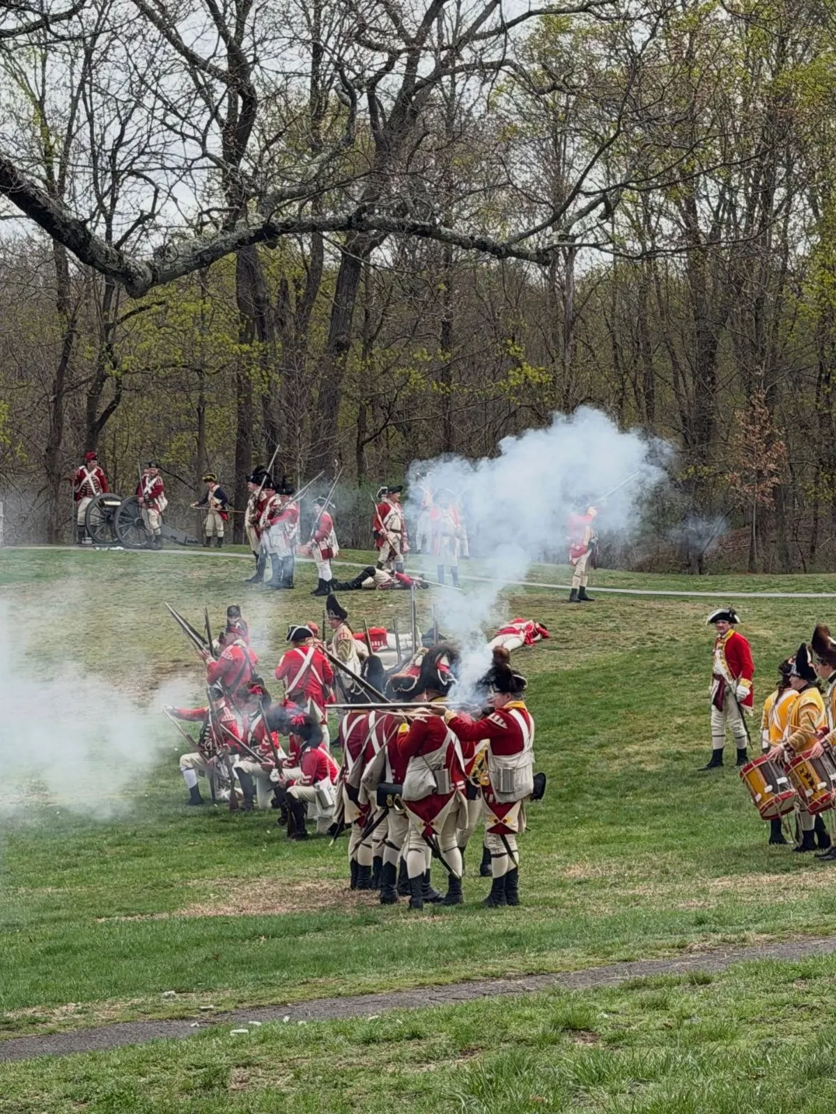 A costumed soldier firing a vintage rifle during a history demonstration at Fort Mackinac