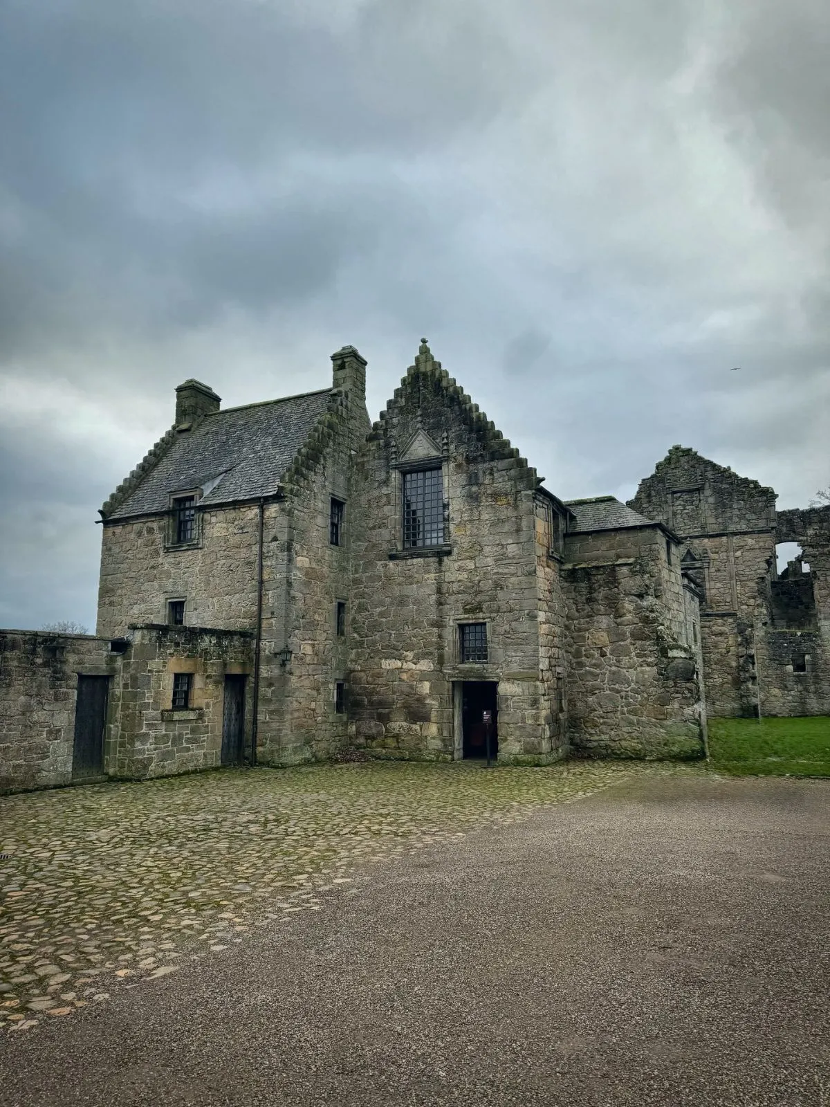 Historic stone ruins of Aberdour Castle surrounded by lush green gardens on the Fife coast near Edinburgh.