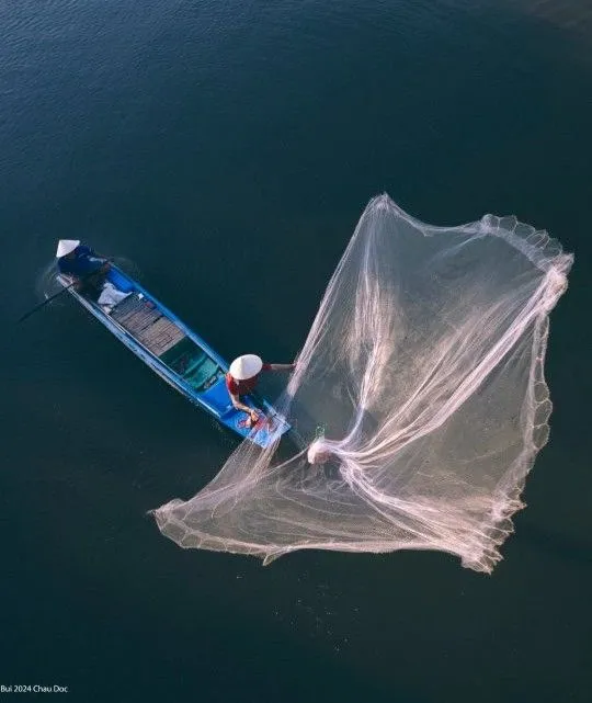Local wooden fishing boat on the shallow shores of Bai Thom