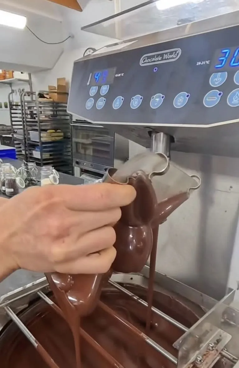 Copper bowls and raw cacao beans in a brightly lit chocolate production room