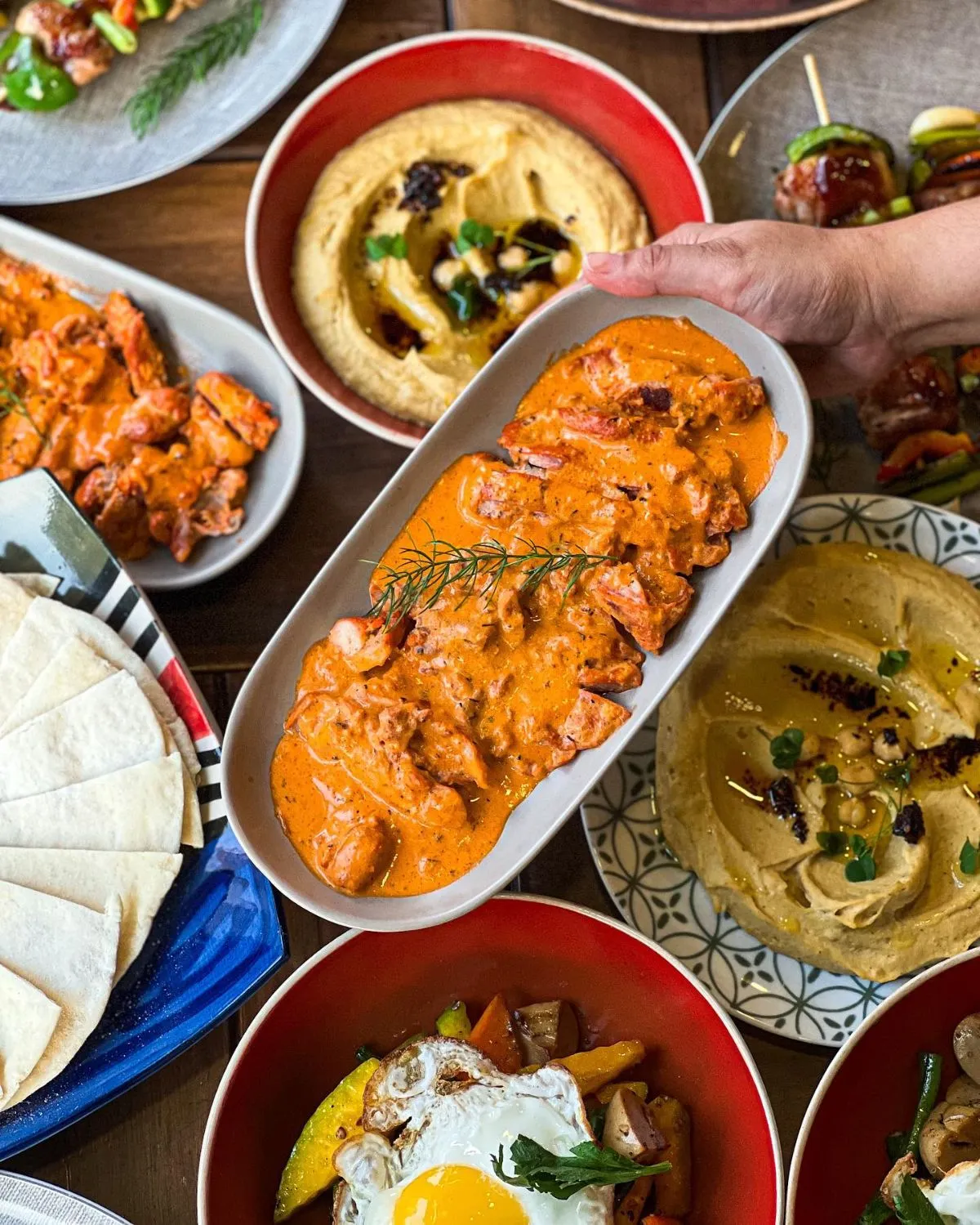 Travelers and locals sharing long wooden tables while dining outdoors