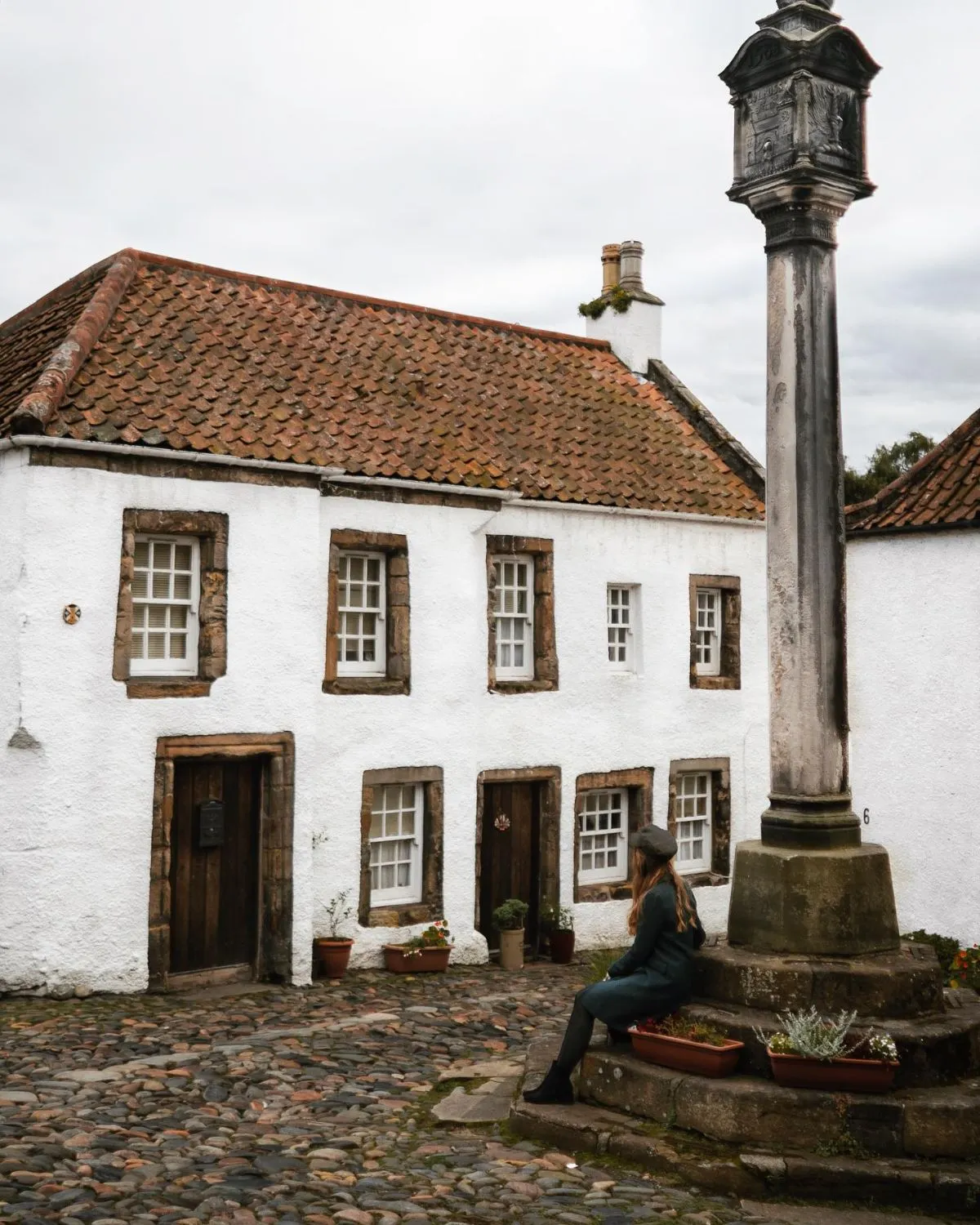 Cobbled square in Culross village with historic white-harled buildings.